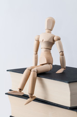 Eine Zeichenpuppe sitzt auf einem Stapel Bücher