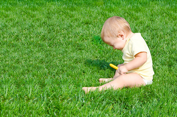 А pretty little boy sneezes sitting on a grass