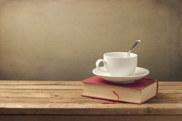 Obraz na płótnie Canvas Filiżanka kawy i książki na drewnianym stole
