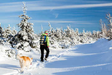 Female hiker walking on snow, winter hiking with dog