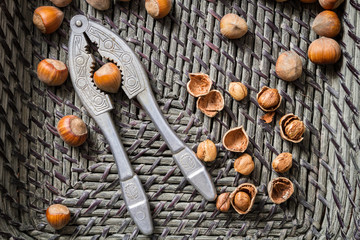 Closeup hazelnuts with nutcracker in old basket