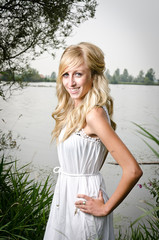 Fototapeta na wymiar hübsche blonde Frau in der Natur in einem weißen Kleid