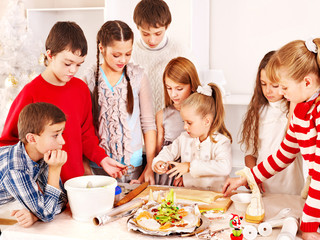 Children rolling dough in kitchen.