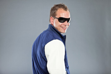 Happy young man with short hair wearing black sunglasses.