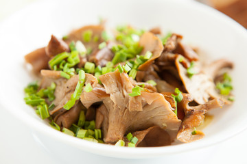 Fried chanterelles with green onions in a white bowl