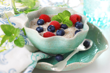 Oatmeal with fresh berries in ceramic dish.