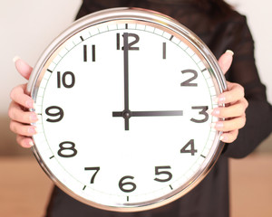 Frau hält rießige Uhr in der Hand