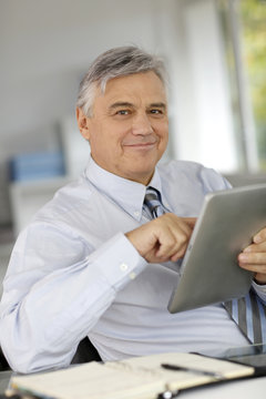 Senior businessman in office using tablet