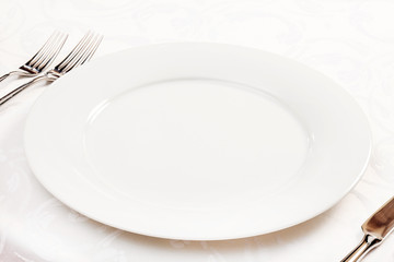 White empty plate with fork and knife