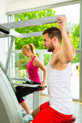 Fitnessstudio - Leute beim Sport am Gerät 