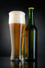 Mug and bottle of beer over black background