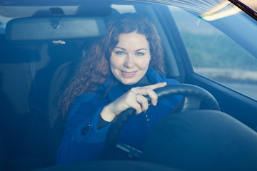 Smiling young woman the driver looking through car windglass