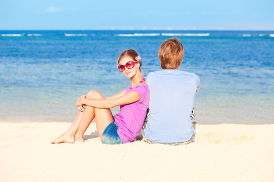 beautiful young couple sitting and having fun on beach