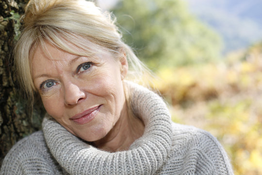 Portrait Of Senior Woman Leaning Against Tree