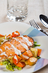 fried salmon on a garden salad topped with fresh butter