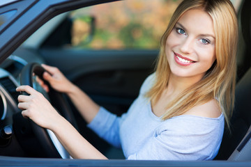 Fototapeta na wymiar Uśmiechnięta młoda kobieta siedzi w samochodzie