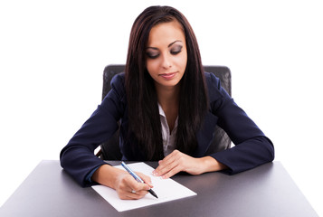 Beautiful businesswoman writing while sitting at desk isolated o