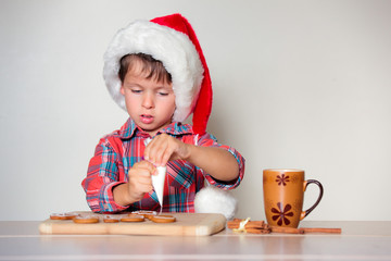 Cute little boy decorating the gingerbread cookies