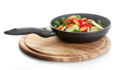 frying pan with vegetables on white