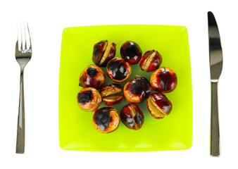 roasted chestnuts in the green plate with fork and knife