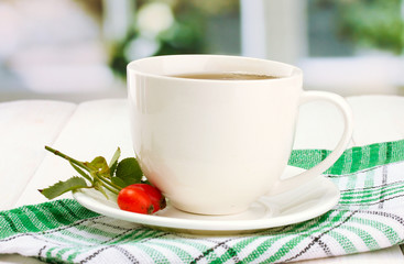 cup of tea with hip roses, on wooden table