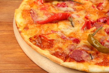 Tasty pepperoni pizza on wooden board on wooden background