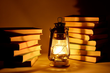 Burning kerosene lamp and books, concept magic of light