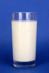 Glass of fresh new milk on blue background