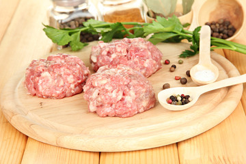 Raw meatballs with spices on wooden table