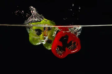 Photo sur Plexiglas Éclaboussures deau Tranches de poivrons rouges et verts frais tombant dans l& 39 eau