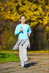 A young girl jogging in the park along trees