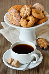 Cup of coffee and delicious homemade cookie on a cake stand.