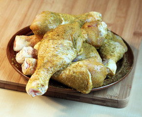 Raw spiced chicken legs on a wooden chopping board