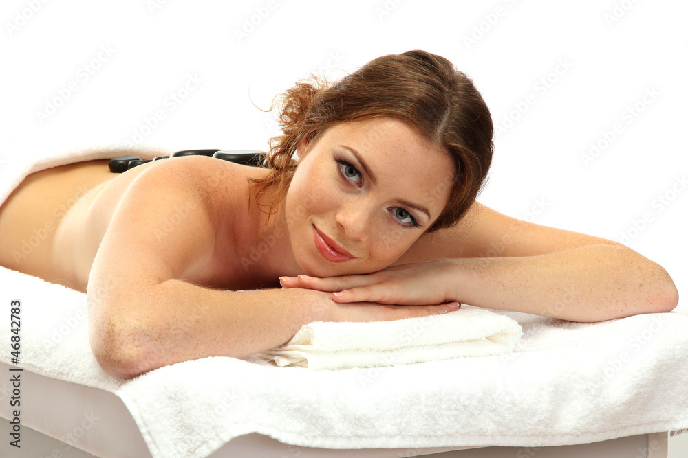 Wall mural beautiful young woman in spa salon with spa stones, isolated