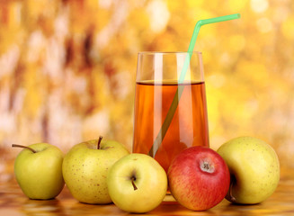 Useful apple juice with apples around on autumn background