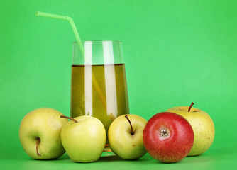 Useful apple juice with apples around on green background