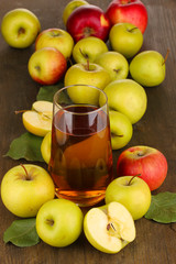 Useful apple juice with apples around on wooden table
