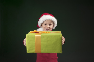 boy with christmas hat and present on dark green