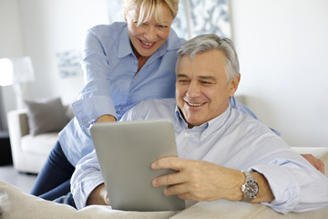 Modern senior couple websurfing on tablet