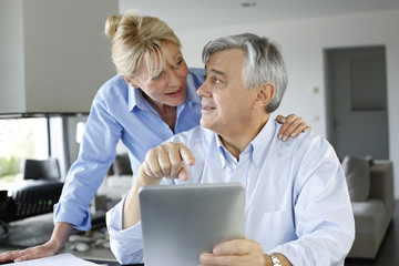 Senior couple looking at bank account on digital tablet - obrazy, fototapety, plakaty