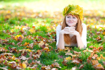 young redhead teenager woman in a wreath of maple leaves lying o