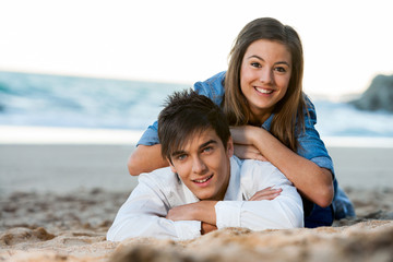 Young couple relaxing on beach at sunset.