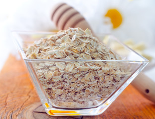 Raw oat flaks in the glass bowl
