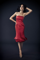 Fototapeta premium Beautiful Woman In Res Rose Dress On Dark Background