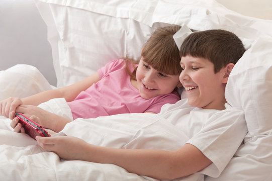 Children in bed playing game console. Close-up.