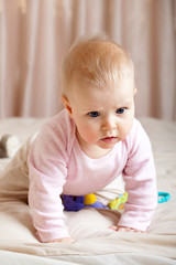 Fototapeta premium Portrait of curious baby girl crawling on bed, closeup shot