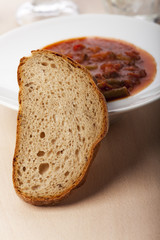 Brotscheibe vor Gulaschsuppe