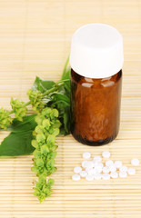 medicine bottle with tablets and flowers on bamboo mat