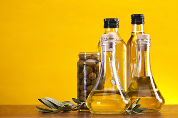 Olive oil and olives set on yellow background