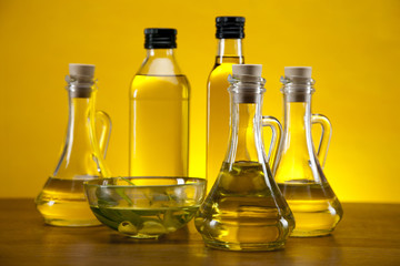 Olive oil and olives set on yellow background